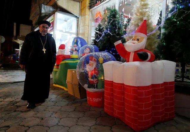 Iraqi priest walks past a market for Christmas decorations in the northern Iraqi city of Erbil, December 23, 2016. (Photo by Ammar Awad/Reuters)