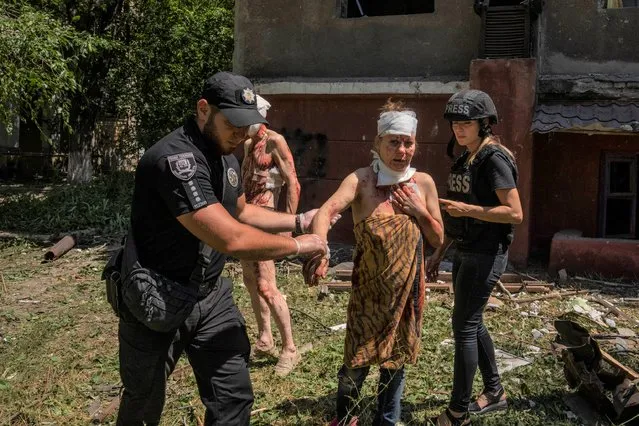 A police officer helps an injured woman after a strike hit a residential area, in Kramatorsk, Donetsk region, eastern Ukraine, Thursday, July 7, 2022. (Photo by Nariman El-Mofty/AP Photo)