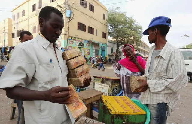 Dealers carry bundles of Somalian currency (shillings) from at an open forex bureau along Hamarweyne district of in Somalia's capital Mogadishu, January 27, 2016. (Photo by Feisal Omar/Reuters)