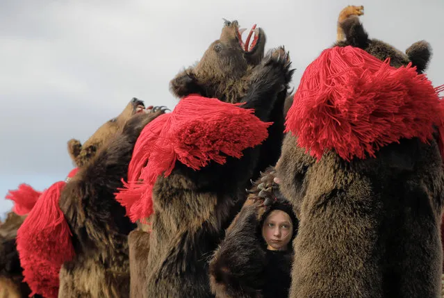 A child wearing a bear costume dances with adults during an annual ritual in Comanesti, Romania, on Friday, December 30, 2016. In pre-Christian rural traditions, dancers wearing colored costumes or animal furs, went from house to house in villages singing and dancing to ward off evil. Today, the tradition also has moved to Romania's cities, where dancers travel to perform the ritual for money. (Photo by Vadim Ghirda/AP Photo)