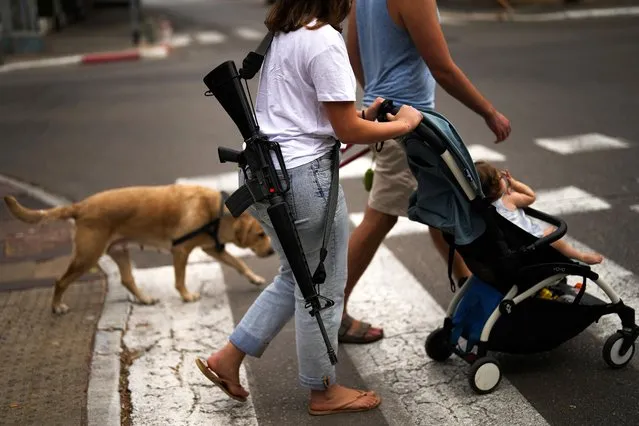 Yehudit, an off-duty Israeli soldier, pushes a trolley with her niece as they stroll in center Tel Aviv, Israel, Friday, October 27, 2023. (Photo by Francisco Seco/AP Photo)