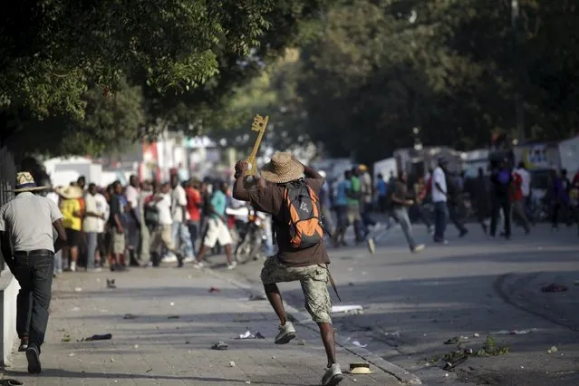 A protester carrying a big fake key runs away from National Police officers near the National Palace during a demonstration called up by opposition groups in Port-au-Prince, Haiti, February 6, 2016. (Photo by Andres Martinez Casares/Reuters)