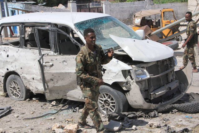 Somali soldiers walk near a vehicle, at the scene of a suicide car bomb attack in Mogadishu, Somalia, Monday, January 2, 2017. A suicide bomber detonated an explosives-laden vehicle at a security checkpoint near Mogadishu's international airport Monday, killing at least three people, a Somali police officer said. (Photo by Farah Abdi Warsameh/AP Photo)
