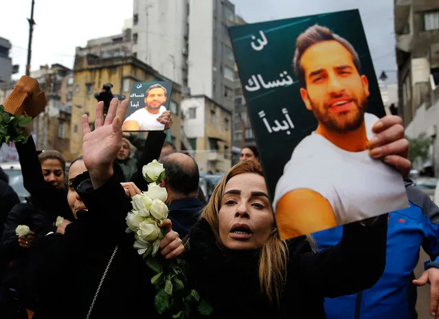 The sister of Elias Wardini, a Lebanese man who was killed in the New Year's Eve Istanbul nightclub attack, mourns as she holds her brother's portrait during his funeral procession, in Beirut, Lebanon, Tuesday, January 3, 2017. The gunman killed 39 people, most of them foreigners, including three Lebanese citizens, at the Istanbul nightclub. Arabic reads, “We will not ever forget you”. (Photo by Hussein Malla/AP Photo)