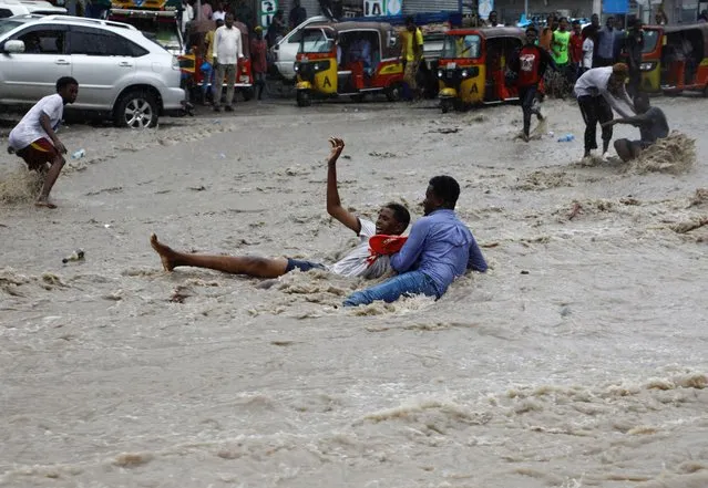 A man attempts to rescue a boy from raging flood waters following heavy rains in Mogadishu, Somalia on November 9, 2023. (Photo by Feisal Omar/Reuters)