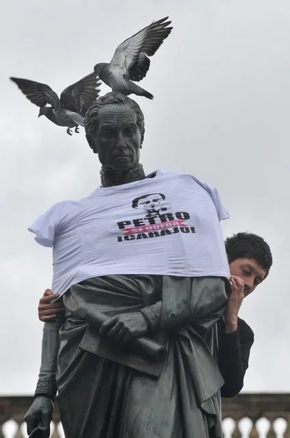 A supporter of Bogota Mayor Gustavo Petro places a T-shirt reading “Petro stays, damn it!” on a statue of South American liberator Simon Bolivar in downtown Bogota on December 9, 2013. Petro was removed from office by the Attorney General and barred for 15 years, due to a scandal involving the city garbage collection. (Photo by Guillermo Legaria/AFP Photo)