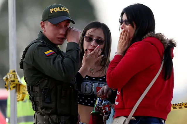 A police officer and two women wipe their tears close to the scene where a car bomb exploded, according to authorities, in Bogota, Colombia January 17, 2019. (Photo by Luisa Gonzalez/Reuters)