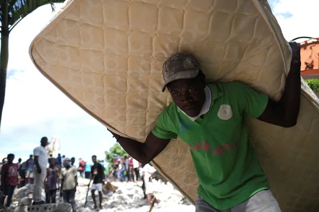 A man carries a mattress from the site of a collapsed hotel after Saturday's 7.2 magnitude quake, in Les Cayes, Haiti on August 16, 2021. (Photo by Ricardo Arduengo/Reuters)