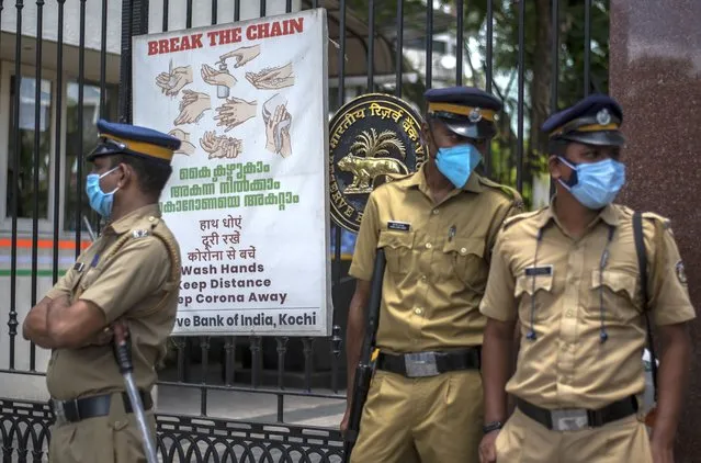Police personnel wearing masks guard outside the Reserve Bank of India during a protest against the federal government's plan to privatize government assets in Kochi, Kerala state, India, Tuesday, August 31, 2021. (Photo by R.S. Iyer/AP Photo)