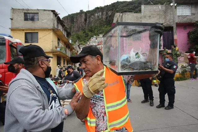 A man evacuates a turtle during search and rescue efforts at the site of a landslide that brought tons of massive boulders down on a steep hillside neighborhood, in Tlalnepantla, on the outskirts of Mexico City, Saturday, September 11, 2021. A section of the peak known as Chiquihuite gave way Friday afternoon, plunging rocks the size of small homes onto the densely populated neighborhood. (Photo by Ginnette Riquelme/AP Photo)