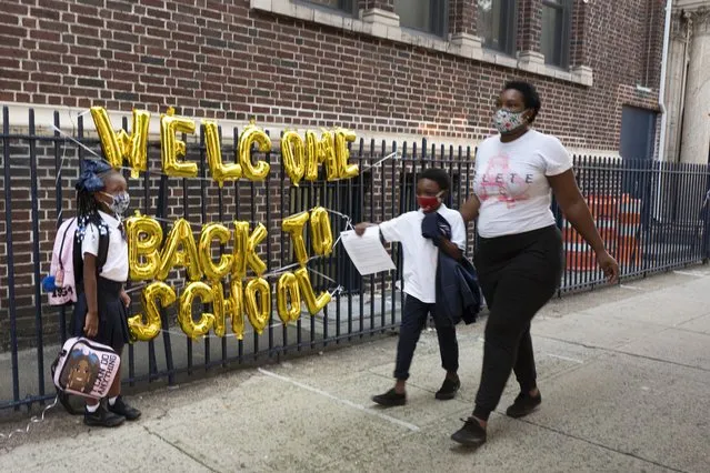A “Welcome Back to School” hangs on a fence at Brooklyn's PS 245 elementary school as children arrive for the first day of class, Monday, September 13, 2021, in New York. Classroom doors are swinging open for about a million New York City public school students in the nation's largest experiment of in-person learning during the coronavirus pandemic. (Photo by Mark Lennihan/AP Photo)