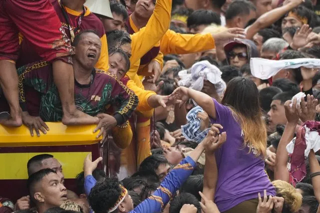 A devotee reacts as he tries to block other devotees from climbing the cart carrying the Black Nazarene during it's annual procession which was resumed after a three-year suspension due to the coronavirus pandemic on Tuesday, January 9, 2024 in Manila, Philippines. (Photo by Aaron Favila/AP Photo)