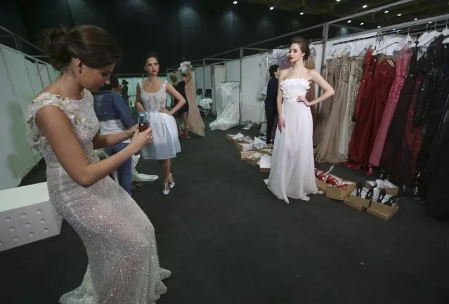 A model, left, takes a picture of her colleague, right, in the backstage as they prepare to display creations by Lebanese international designer Abed Mahfouz during his Spring-Summer 2015 fashion show in Beirut, Lebanon, Wednesday, April 29, 2015. (Photo by Hussein Malla/AP Photo)