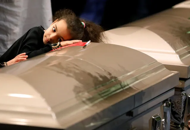 A young mourner lays her head on one of the caskets during funeral services for three of the victims of the deadly shooting at the Quebec Islamic Cultural Centre, at the Congress Centre in Quebec City, Quebec, February 3, 2017. (Photo by Mathieu Belanger/Reuters)