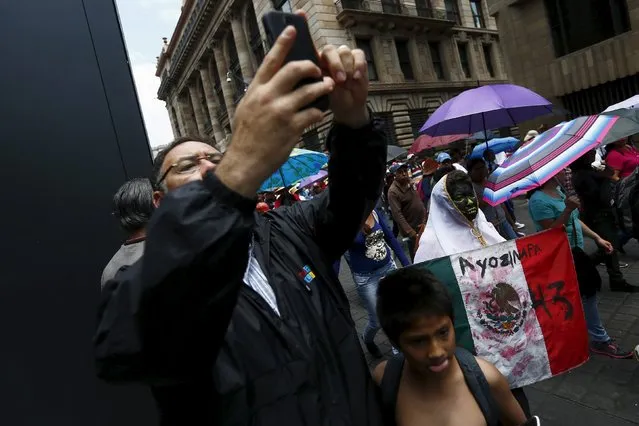 A woman holds a Mexico flag as a man takes a selfie picture during a march for Labor Day in Mexico City May 1, 2015. (Photo by Edgard Garrido/Reuters)