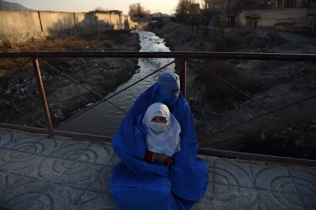 An Afghan woman holds a child as she begs on a bridge in Kabul on February 16, 2016. (Photo by Wakil Kohsar/AFP Photo)