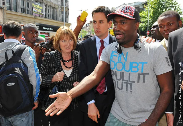 Labour leader Ed Miliband (C) and Deputy Leader of the Labour Party Harriet Harman (centre L) speak with Stafford Blake (right)speaks with Stafford Blake (R) from Peckham while visiting the area where rioting took place during the night before on August 9, 2011 in Peckham, south east London, England