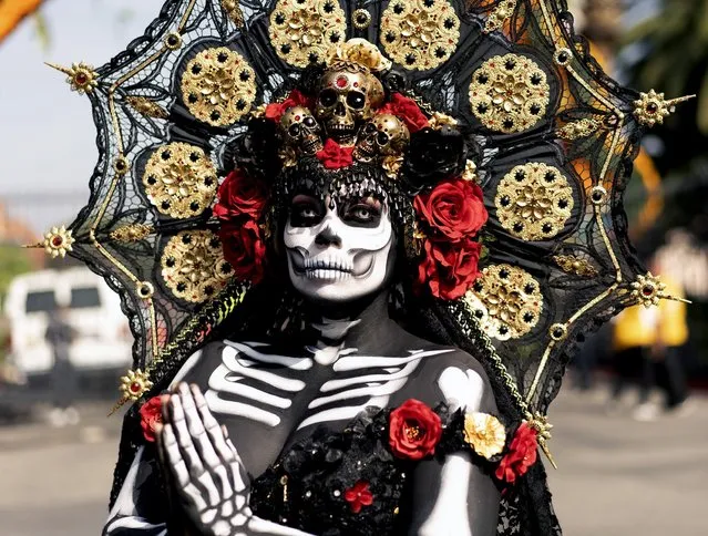 Dressed in traditional make-up and costume a woman participates in the celebration for the Day of the Dead or Día de los Muertos at the Hollywood Forever Cemetery in Los Angeles on Saturday, October 30, 2021. Day of the Dead, is a Mexican holiday where families welcome back the souls of their deceased relatives for a brief reunion that includes food, drink and celebration. (Photo by Richard Vogel/AP Photo)