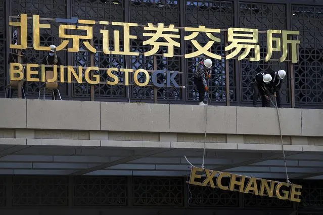 Workers install the nameplate of the Beijing Stock Exchange on the Financial Street in Beijing, Sunday, November 14, 2021. According the local news report, the Beijing Stock Exchange will start trading on Monday, Nov. 15.  (Photo by Andy Wong/AP Photo)