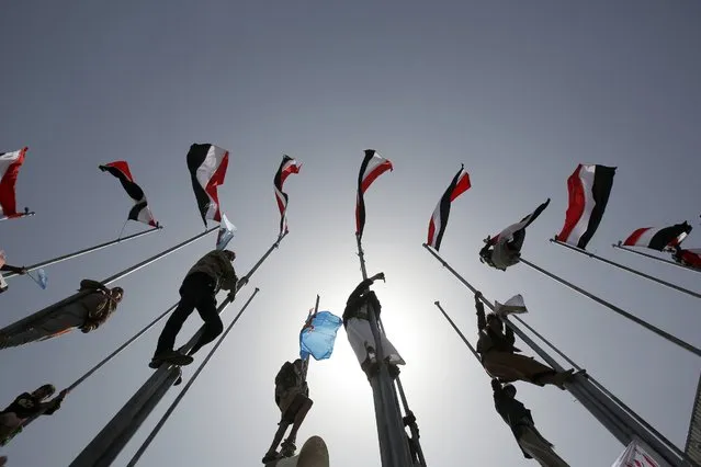 Supporters of Yemen's former President Ali Abdullah Saleh, who are allies of Shiite rebels known as Houthis, climb flag poles during a rally to mark the first anniversary of the Saudi-led military campaign against them, in Sanaa, Yemen, Saturday, March 26, 2016. On Friday, in his first speech in months, the leader of the Houthi rebels called for street rallies to mark the occasion. Yet his tone was comparatively subdued, suggesting that the Houthis are under pressure following yearlong airstrikes and a ground operation that have killed thousands of civilians. (Photo by Hani Mohammed/AP Photo)