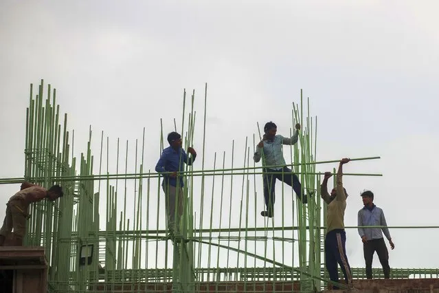 Laborers work at a building construction site in Mumbai, India, Tuesday, November 30, 2021. (Photo by Rafiq Maqbool/AP Photo)