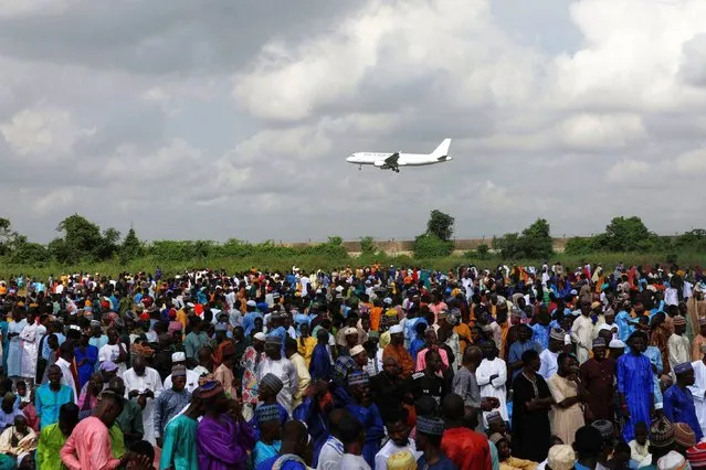 An aircraft flies above Muslim faithful as they attend the Eid al-Fitr prayers, marking the end of Ramadan, in Lagos, Nigeria on April 10, 2024. (Photo by Temilade Adelaja/Reuters)