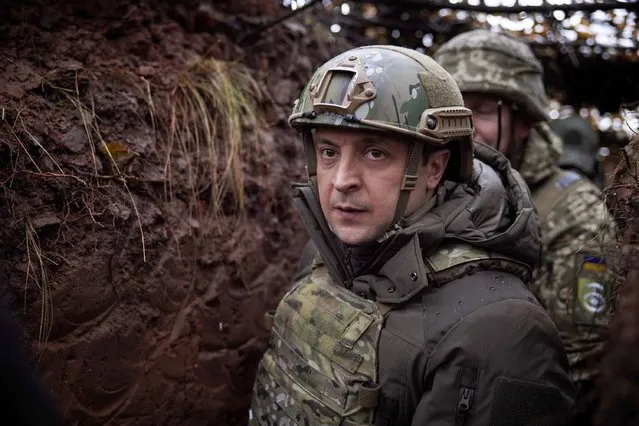 Ukrainian President Volodymyr Zelenskyy, walks under a camouflage net in a trench as he visits the war-hit Donetsk region, eastern Ukraine, Monday, December 6, 2021. (Photo by Ukrainian Presidential Press Office via AP Photo)