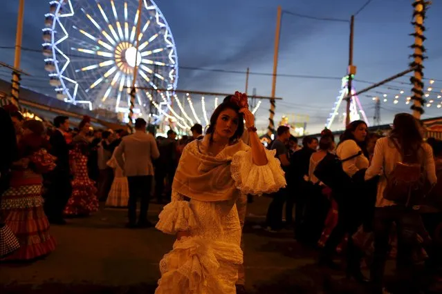 A woman wearing a sevillana dress walks during the traditional Feria de Abril (April fair) in the Andalusian capital of Seville, southern Spain, April 13, 2016. (Photo by Marcelo del Pozo/Reuters)