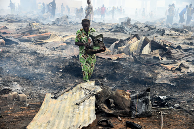 A local resident attempts to salvage a stove from the fire in the biggest Lagos wood market, Oko-Baba Sawmill, in Ebute-Metta, district of Lagos, on January 5, 2022. The largest Lagos wood market, Oko-Baba Sawmill at Ebute Metta, Nigeria's commercial hub, was razed by fire early on January 5, 2022, destroying valuables and displacing sawmillers, traders and hundreds of residents of the sawmill and the neighbourhood. (Photo by Pius Utomi Ekpei/AFP Photo)