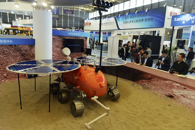 In thi November 4, 2014, file photo, visitors to the 16th China International Industry Fair (CIIF) look at a prototype of what a Chinese Mars rover would look like in Shanghai, China. Head of the China National Space Administration Xu Dazhe said Friday, April 22, 2016 at a rare news conference that plans are being drawn up for the project that was formally announced in January and that it has the government's full support. (Chinatopix via AP Photo)