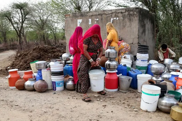 In this photo taken on on May 16, 2019, Indian villagers collect drinking water from a road side water tap on the outskirts village of Ajmer, in the Indian state of Rajasthan. Senior officials in the Public Health and Engineering Department (PHED) claimed on May 15 that the water crisis in the state of Rajasthan does not warrant a situation of running water trains and the priority now is to supply drinking water by tankers, local reports said. (Photo by Himanshu Sharma/AFP Photo)