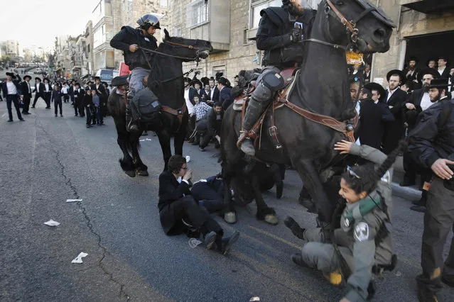 Israeli mounted policemen run over a police woman as he disperses ultra- Orthodox Jews during a protest against Israeli army conscription, in the centre of Jerusalem, on April 3, 2017. Many ultra- Orthodox oppose military service for their young men because they believe it exposes them to influences and temptations not found in the insular world of prayer and religious study. (Photo by Menahem Kahana/AFP Photo)
