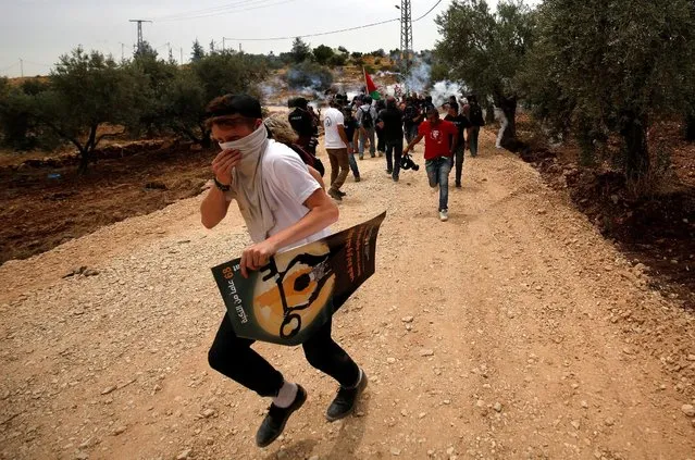 A foreign activist runs for cover from tear gas fired by Israeli troops during clashes at a protest ahead of Nakba day, in the West Bank village of Bilin near Ramallah May 13, 2016. (Photo by Mohamad Torokman/Reuters)