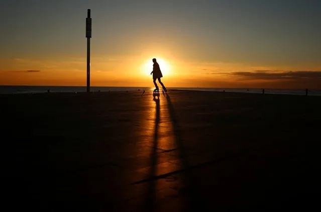 A woman skates during sunrise at the sidewalk of Barceloneta beach, amid the outbreak of the coronavirus disease (COVID-19), in Barcelona, Spain, February 1, 2022. (Photo by Nacho Doce/Reuters)