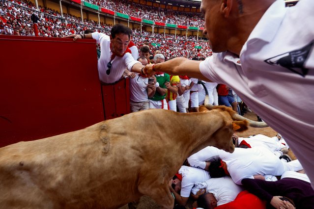 A wild cow jumps over revellers at the San Fermin festival in Pamplona, Spain on July 10, 2024. (Photo by Susana Vera/Reuters)