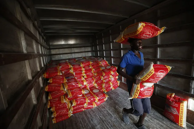 Workers unload sacks of rice at the depot of wholesale business owner Vangly Germeille, in Leogane, Haiti, Saturday, October 5, 2019. (Photo by Rebecca Blackwell/AP Photo)
