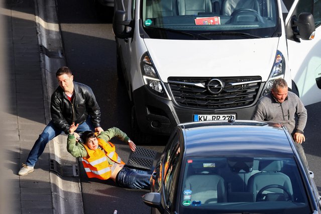 A car driver removes an activist of the “Letzte Generation” (Last Generation) as they block a highway to protest for climate councils, speed limit on highways as well as for affordable public transport, in Berlin, Germany on April 24, 2023. (Photo by Christian Mang/Reuters)