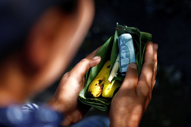 A Tenggerese Hindu woman holds her offerings of money, bananas, and cigarettes, while she prays at an altar near Mount Bromo, ahead of the Yadnya Kasada festival in Probolinggo, East Java, Indonesia, on June 20, 2024. (Photo by Willy Kurniawan/Reuters)