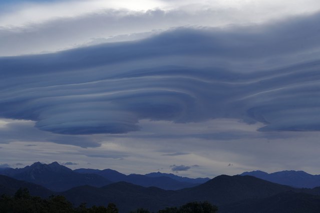 This photograph, taken in Cognocoli-Monticchi on the French Mediterranean island of Corsica on November 14, 2023 shows lenticular clouds above Corsican mountains. (Photo by Pascal Pochard-Casabianca/AFP Photo)