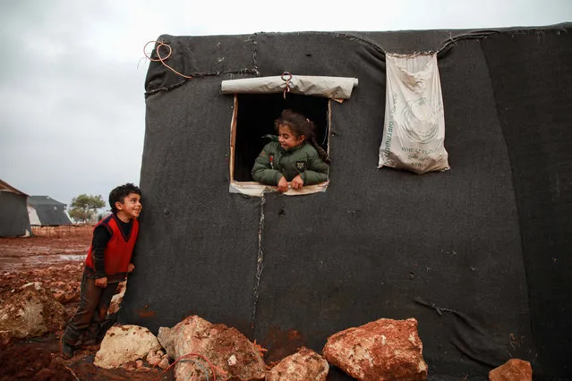 A boy and a girl looking out the window of a tent exchange glances, at a flooded camp for displaced Syrians near the village of Killi in the north of the northwestern Idlib province on December 5, 2019. (Photo by Aaref Watad/AFP Photo)
