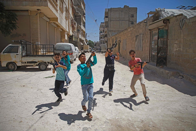 Syrian boys play with plastic guns on the first day of the Muslim religious festival of Eid al-Adha in al-Dana in Syria's rebel-controlled Idlib region, near the border with Turkey, on August 11, 2019. Muslims across the world are celebrating the first day of the Feast of Sacrifice, which marks the end of the hajj pilgrimage to Mecca and commemorates prophet Abraham's sacrifice of a lamb after God spared Ishmael, his son. (Photo by Aaref Watad/AFP Photo)