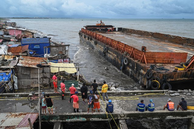 Residents inspect a barge after it was swept ashore due to Tropical Storm Yagi in Rosario, Cavite Province, on September 3, 2024. Floods and landslides killed 11 people after a fierce tropical storm dumped heavy rain on the Philippines for a second day, officials said September 2. (Photo by Jam Sta Rosa/AFP Photo)