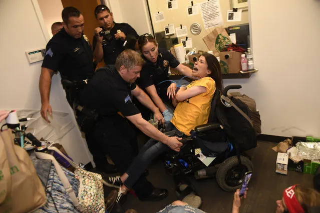 Dawn Russell gets arrested by Denver police officers after refusing the vacate the offices of Senator Cory Gardner on June 29, 2017 in Denver, Colorado. A handful of people, all of whom are with ADAPT, held a sit-in for 58 hours in the tiny front lobby space in the office of Colorado Senator Cory Gardner. They are asking the senator to vote against the new health care bill. As they were arrested protesters chanted “I would rather go to jail than die without Medicaid”. ADAPT is a national grass-roots community that organizes disability rights activists to engage in nonviolent direct action, including civil disobedience, to assure the civil and human rights of people with disabilities to live in freedom.  (Photo by Helen H. Richardson/The Denver Post)