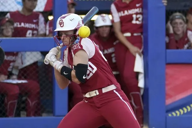 Oklahoma's Jana Johns (20) is hit by a Texas pitch during the first inning of the first game of the NCAA Women's College World Series softball championship series Wednesday, June 8, 2022, in Oklahoma City. (Photo by Sue Ogrocki/AP Photo)