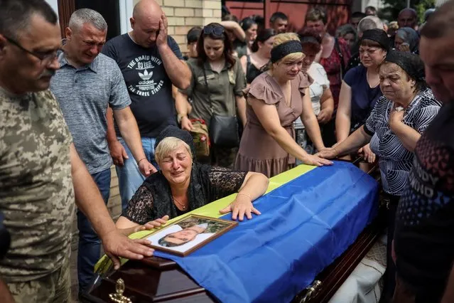 Natalia, the wife of Ukrainian serviceman Volodymyr Kochetov, 46, who was killed in a fight during Russia's invasion, reacts during his funeral in the village of Babyntsi, Ukraine on June 30, 2022. (Photo by Gleb Garanich/Reuters)