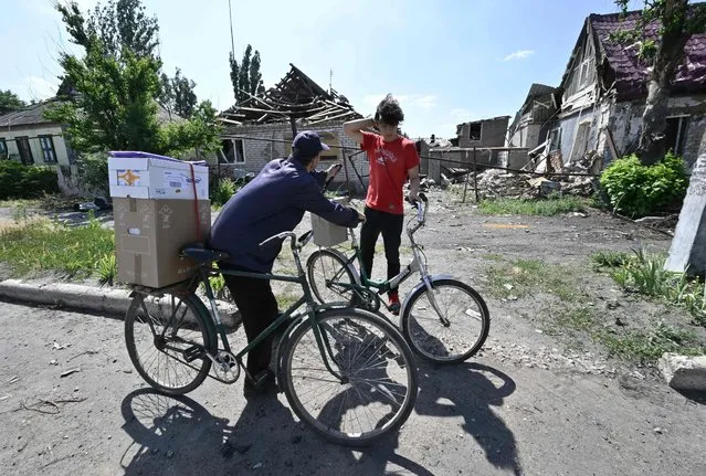 Local residents carry boxes with a humanitarian aid in the town of Siversk, Donetsk Oblast, on July 3, 2022, amid Russian invasion of Ukraine. (Photo by Genya Savilov/AFP Photo)