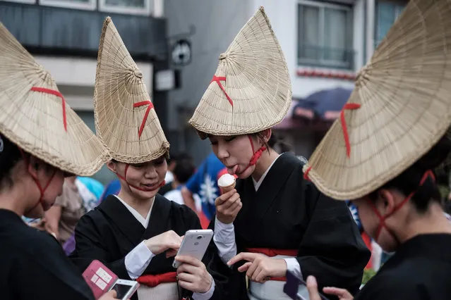 This photo taken on August 14, 2017 shows a dancer (C) eating ice cream during the Awa Odori festival in Tokushima The four- day dance festival attracts more than 1.2 million people annually. (Photo by  Yasuyoshi Chiba/AFP Photo)