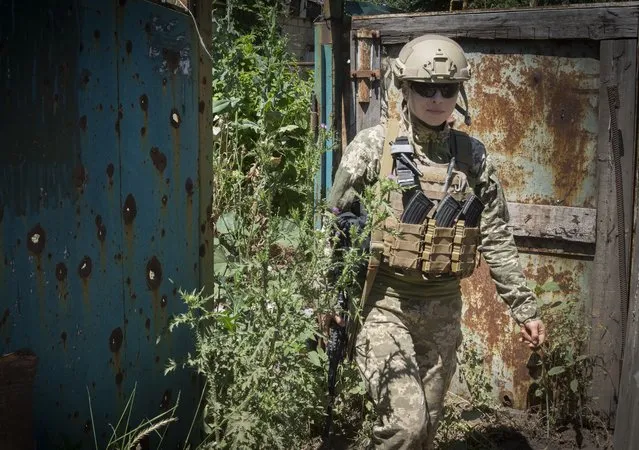 Ukrainian platoon commander Mariia walks in a position in the Donetsk region, Ukraine, Saturday, July 2, 2022. Ukrainian soldiers returning from the frontlines in eastern Ukraine’s Donbas region describe life during what has turned into a grueling war of attrition as apocalyptic. Mariia, 41, said that front-line conditions may vary depending on where a unit is positioned and how well supplied they are. (Photo by Efrem Lukatsky/AP Photo)