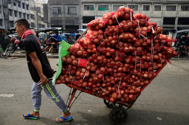 A worker hauls a rack full of sacks of white onions to be delivered to a wet market in Metro Manila, Philippines July 4, 2016. (Photo by Romeo Ranoco/Reuters)