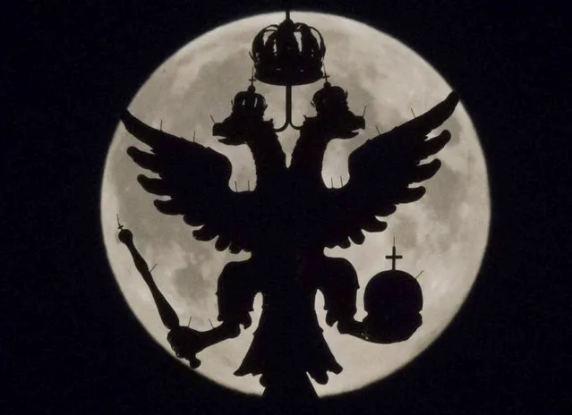 A two-headed eagle, the national symbol of Russia, is seen in front of the supermoon as it rises over the towers of Historical Museum in Moscow August 10, 2014. Occurring when a full moon or new moon coincides with the closest approach the moon makes to the Earth, the Supermoon results in a larger-than-usual appearance of the lunar disk. (Photo by Maxim Shemetov/Reuters)